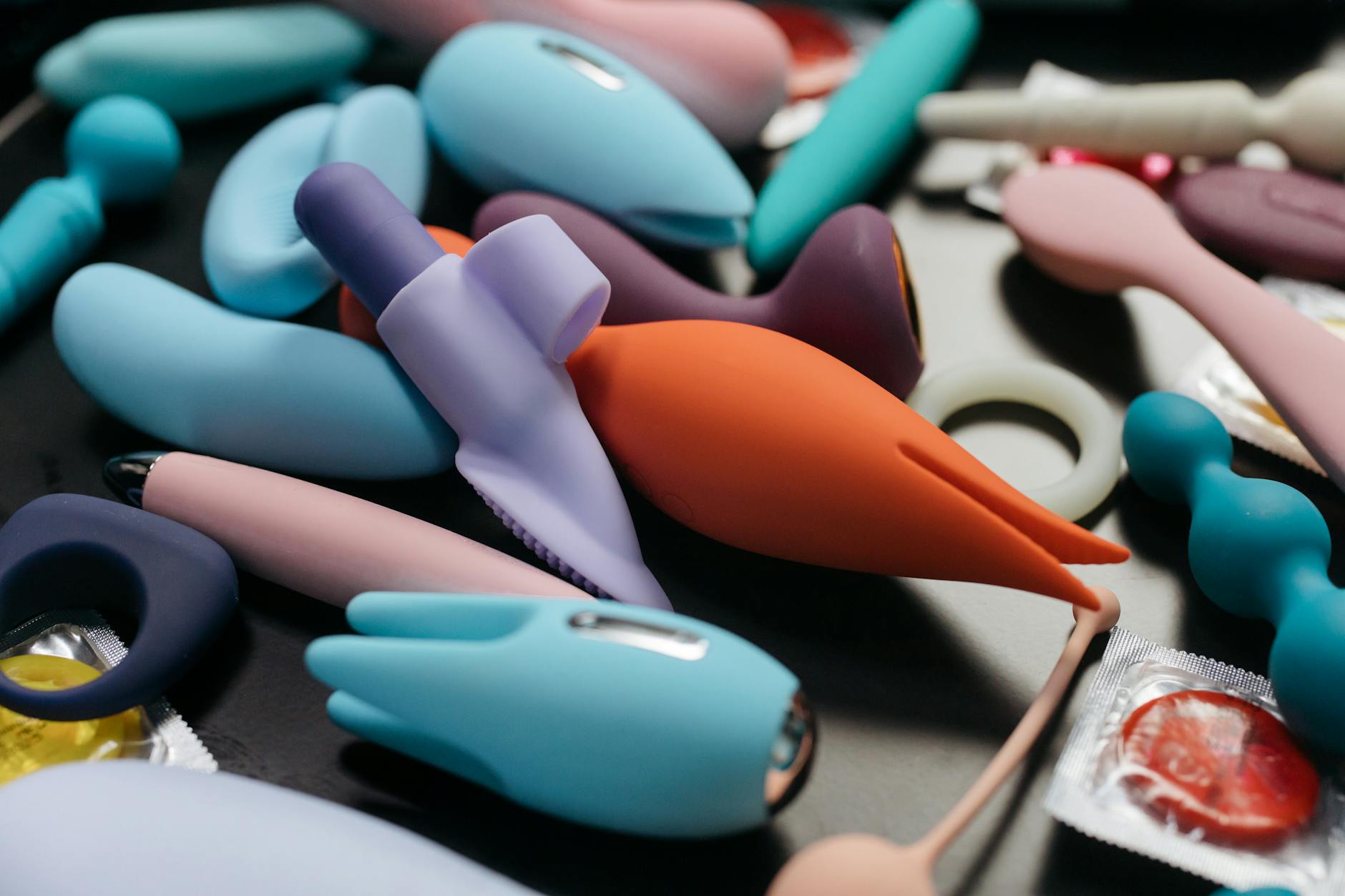 Colorful sex toys arranged on a bright yellow background, showcasing various designs