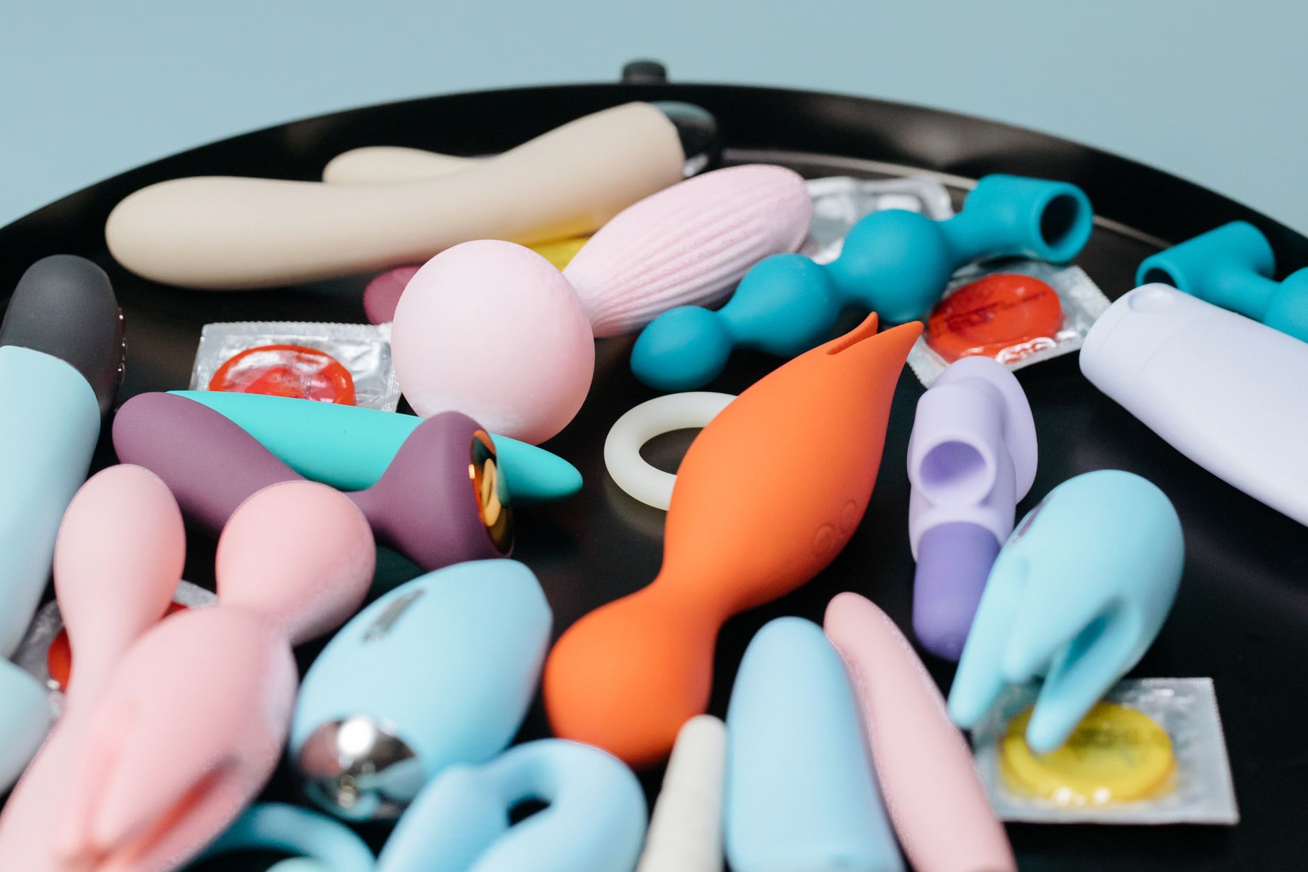 A sleek teal clitoral vibrator on white silk fabric
