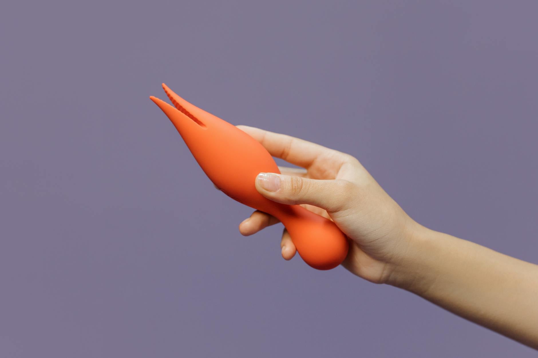 A hand holding a lemon clitoral vibrator against a minimalistic backdrop, representing gentle sensual exploration