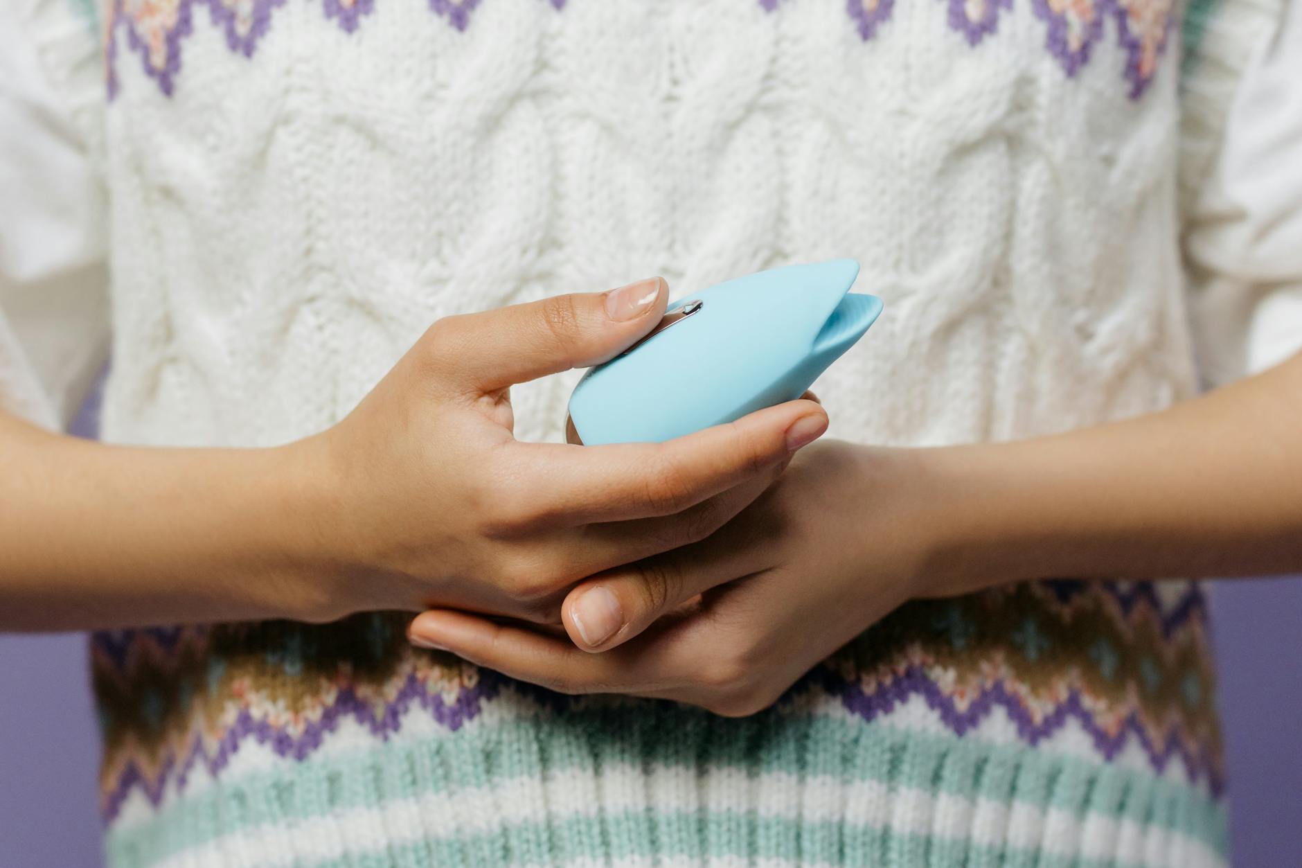 Hands holding a blue personal massager, symbolizing solo pleasure and self-reconnection after loss