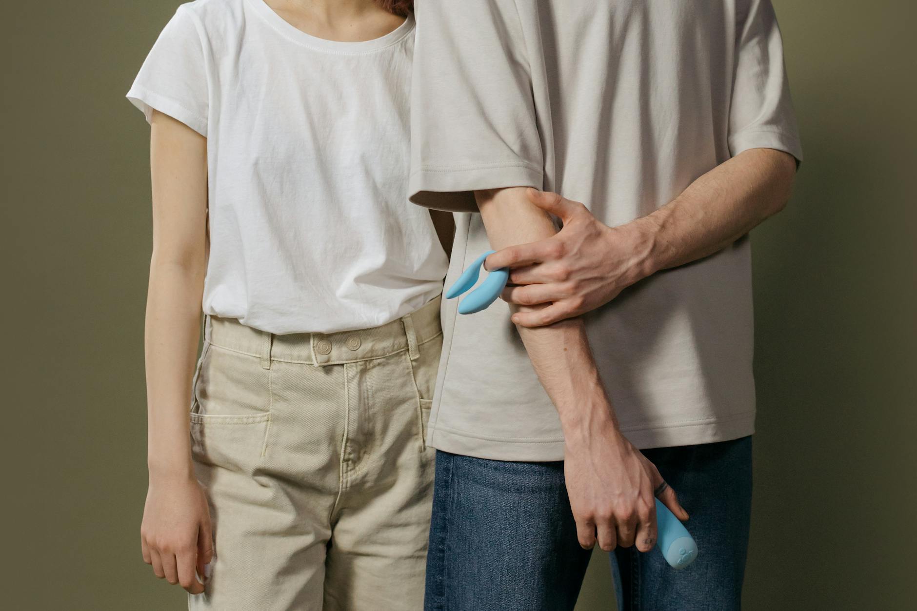 Close-up of a hand holding a blue lemon clitoral vibrator above a decorative glass bowl
