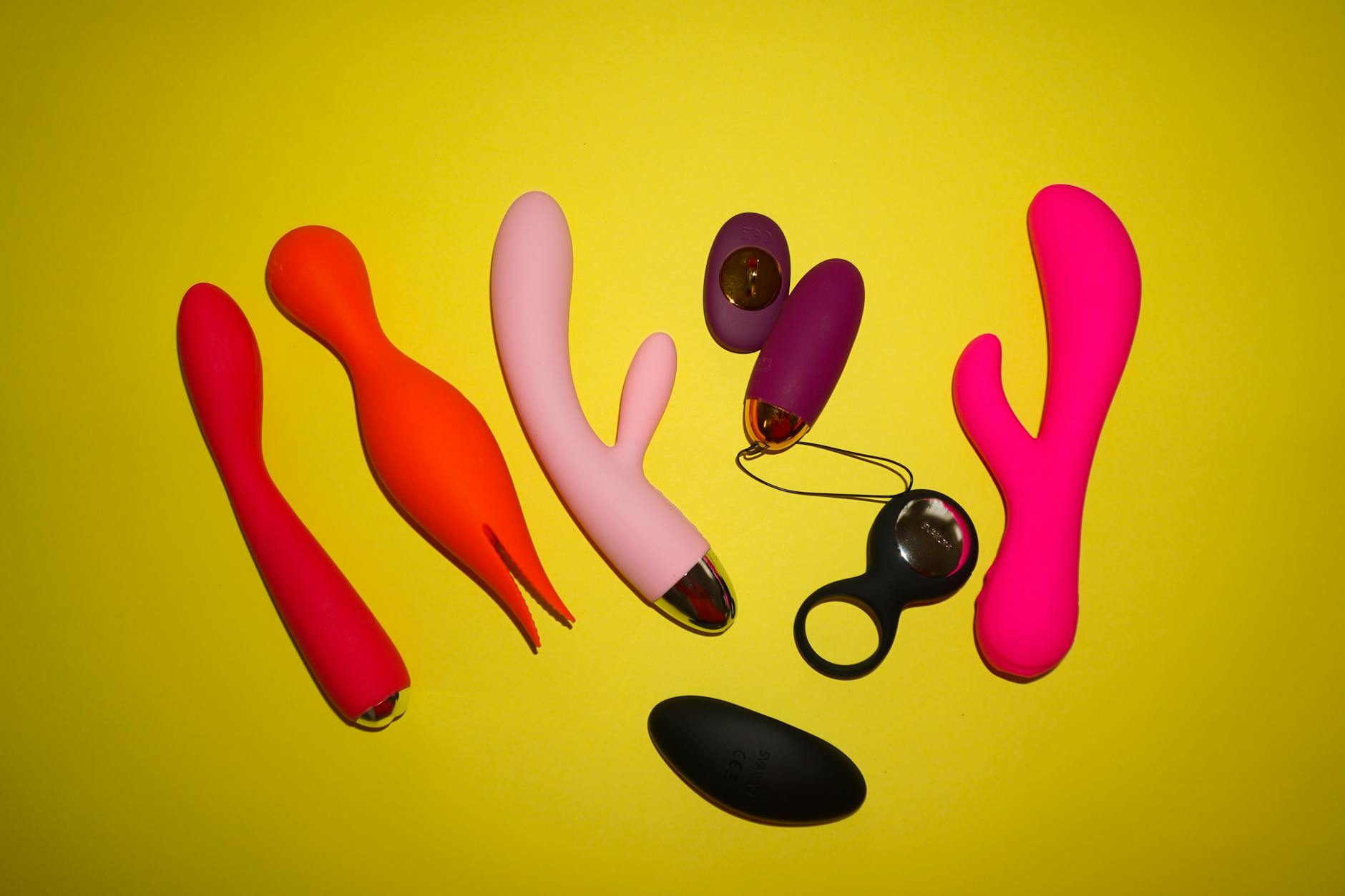 Colorful vibrators arranged on a bright background, representing different tools for pleasure recovery