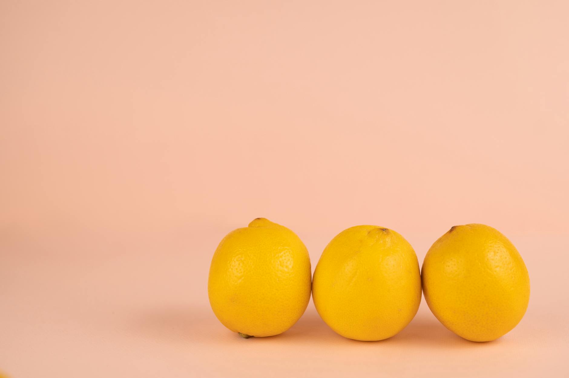 Yellow silicone vibrator surrounded by fruit on a bright yellow background, representing pleasure and sensation